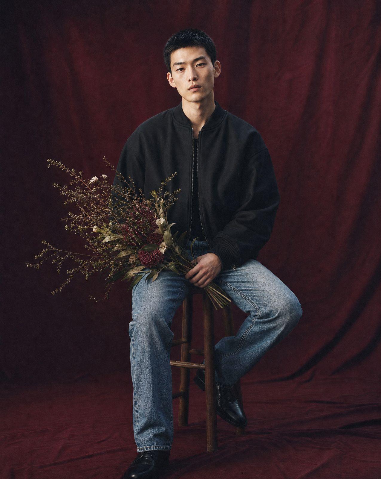 a man sitting on a stool holding a bouquet of flowers