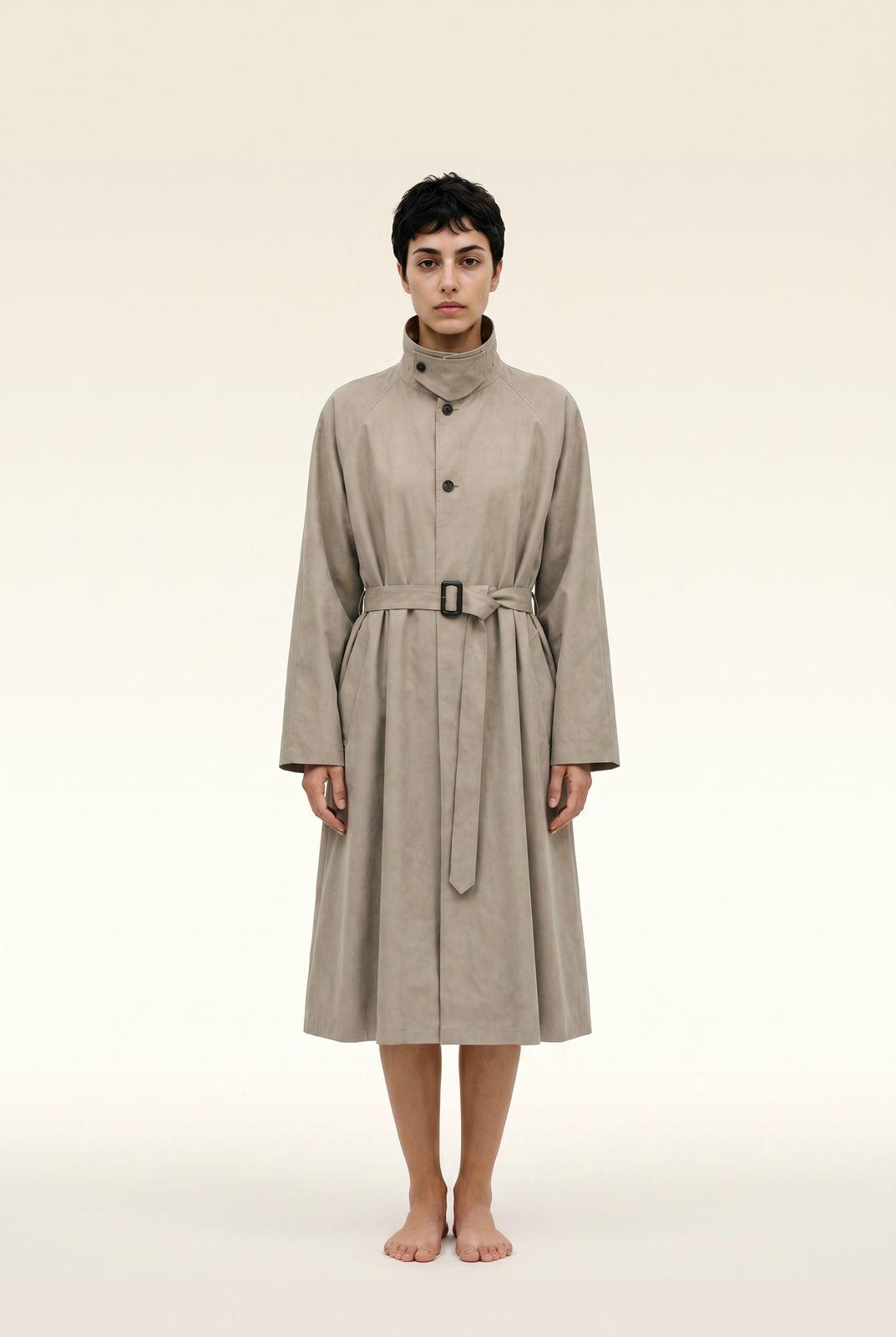 a woman in a trench coat standing in front of a white background