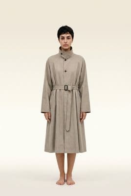 a woman in a trench coat standing in front of a white background