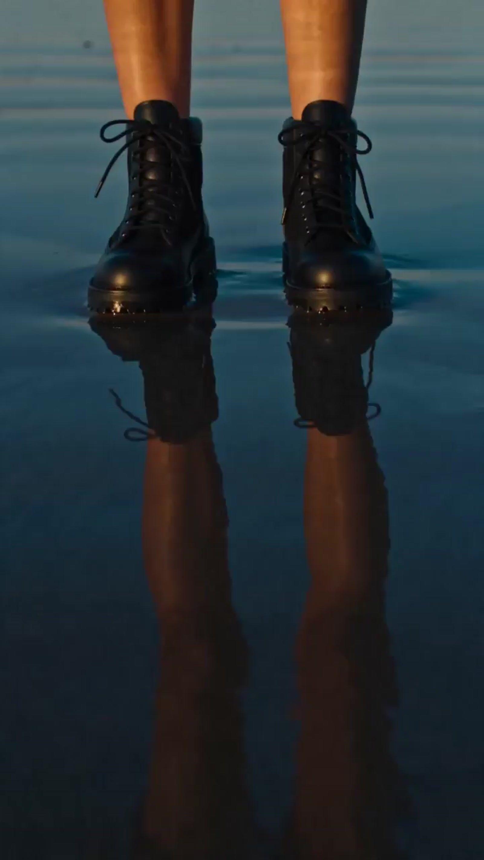 a person standing in the water wearing black shoes