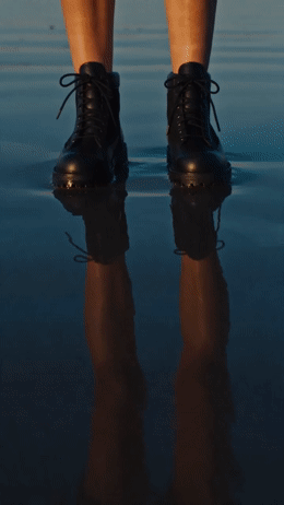 a person standing in the water wearing black shoes