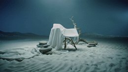 a chair covered in a sheet on top of a sandy beach