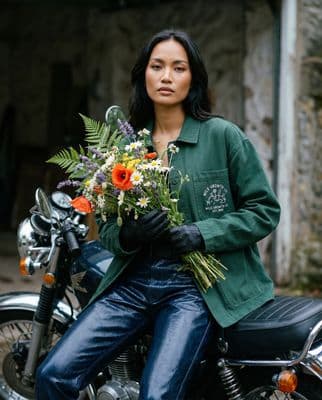 a woman sitting on a motorcycle holding a bunch of flowers