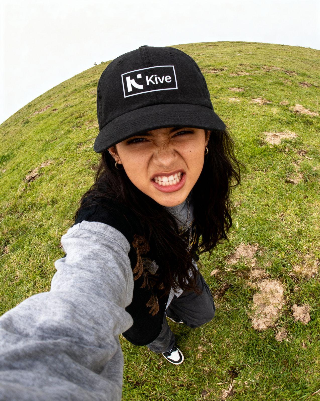a woman in a black hat is standing in the grass