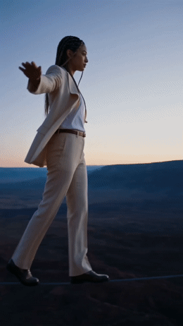 a woman in a white suit walking across a desert