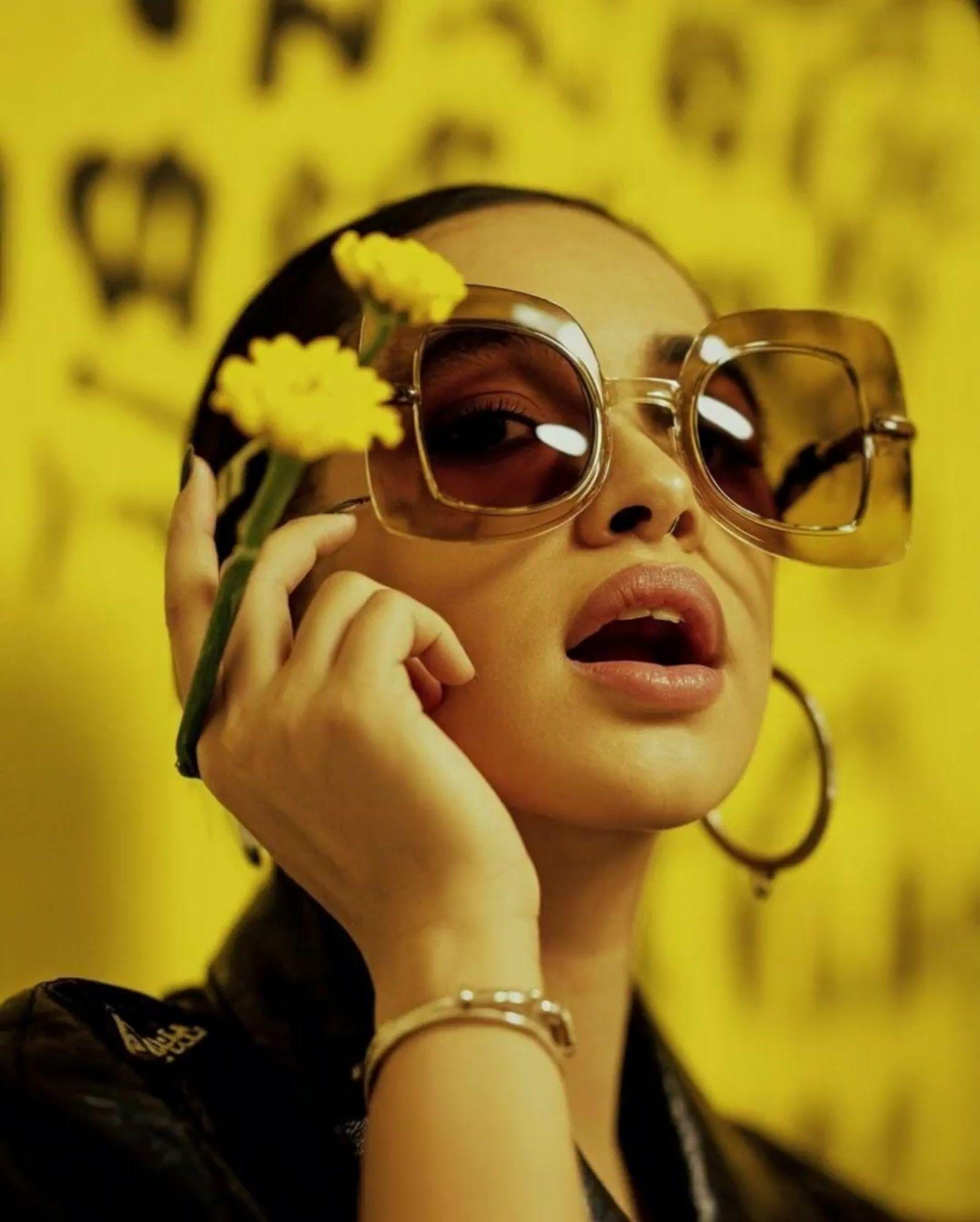 a woman wearing sunglasses and holding a flower