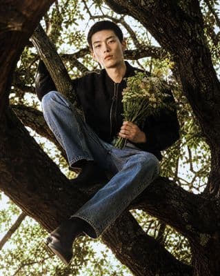 a man sitting in a tree holding a bunch of flowers