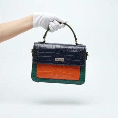 a hand in white gloves holding a blue and orange purse