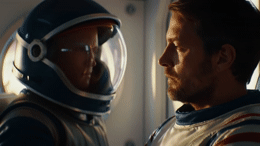 a man in a space suit looking at another man in a space suit