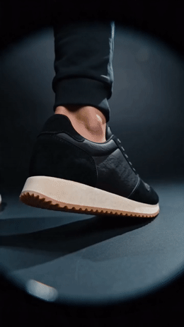a person's feet in a pair of black sneakers