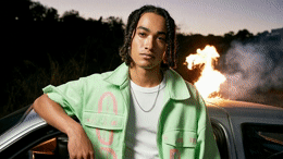 a man with dreadlocks leaning on a car