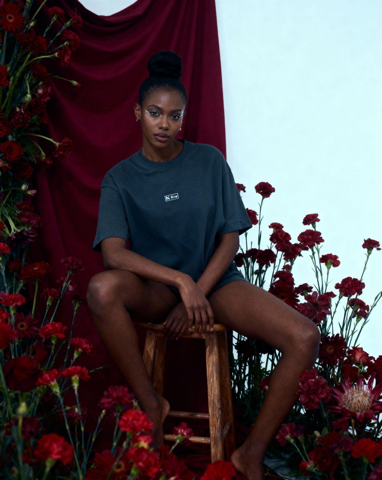 a woman sitting on a stool in front of flowers