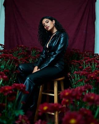 a woman sitting on a stool in front of flowers