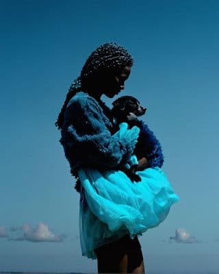 a woman in a blue dress holding a black dog