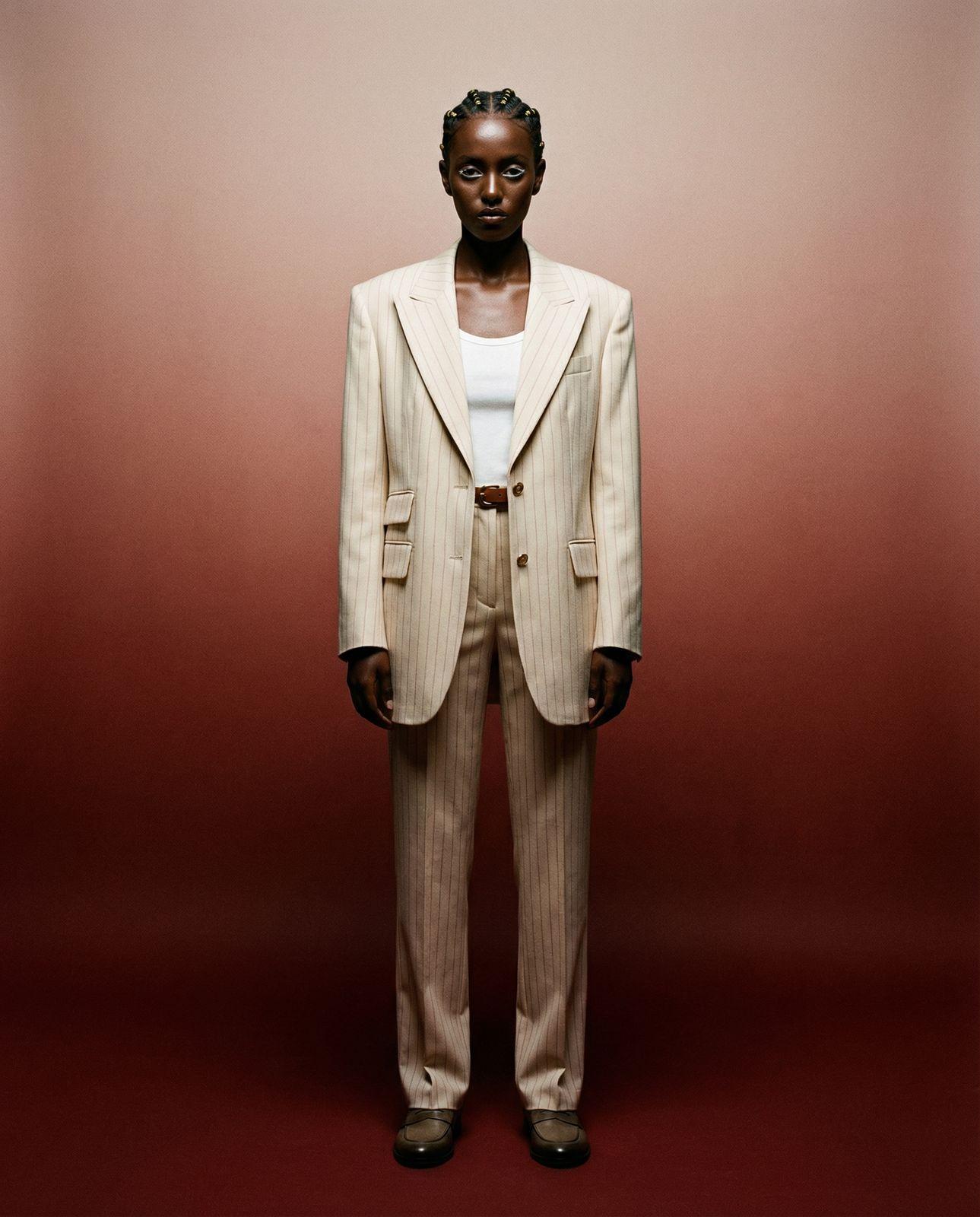 a man in a suit standing in front of a red wall