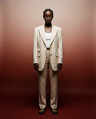 a man in a suit standing in front of a red wall