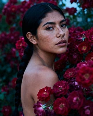 a woman with braids standing in front of flowers