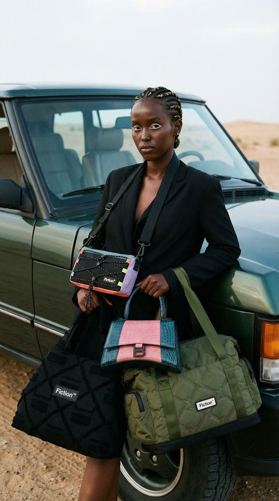 a woman in a black dress holding a green bag