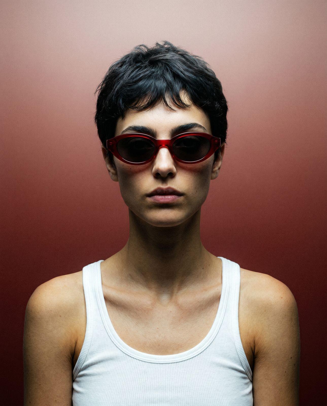 a woman wearing red sunglasses and a white tank top