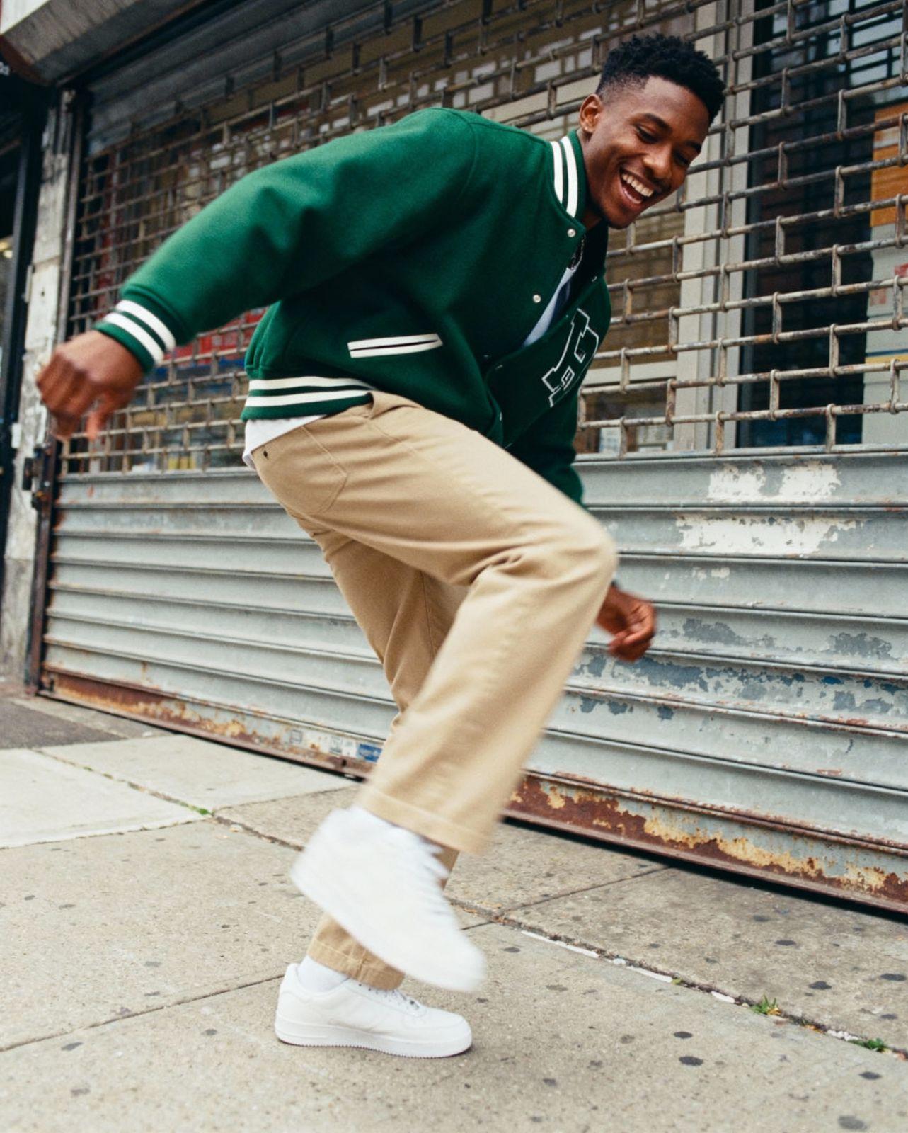 a man in a green sweater is doing a trick on a skateboard