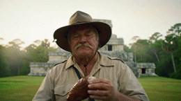 a man wearing a hat and holding a hot dog