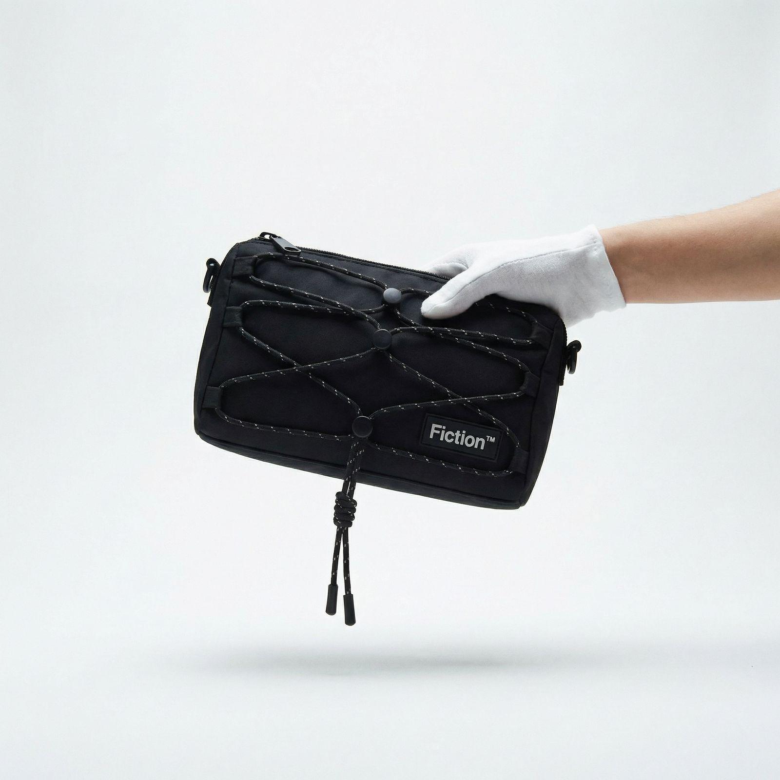 a hand in white gloves holding a black bag