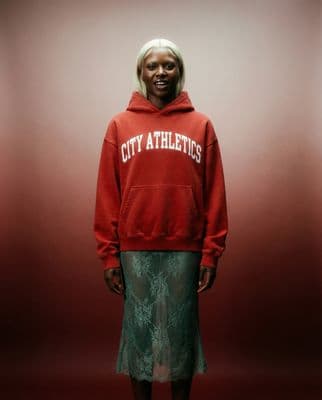 a woman in a red sweatshirt and green skirt