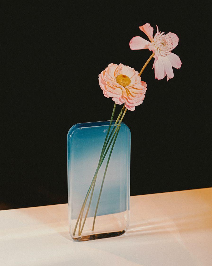 two pink flowers in a blue vase on a table
