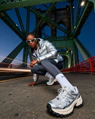 a woman squatting on the ground in front of a bridge