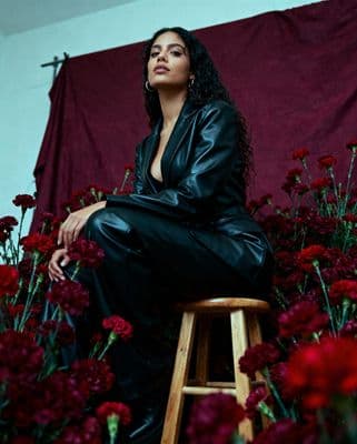 a woman sitting on a stool in front of flowers