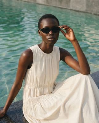 a woman in a white dress sitting by a pool