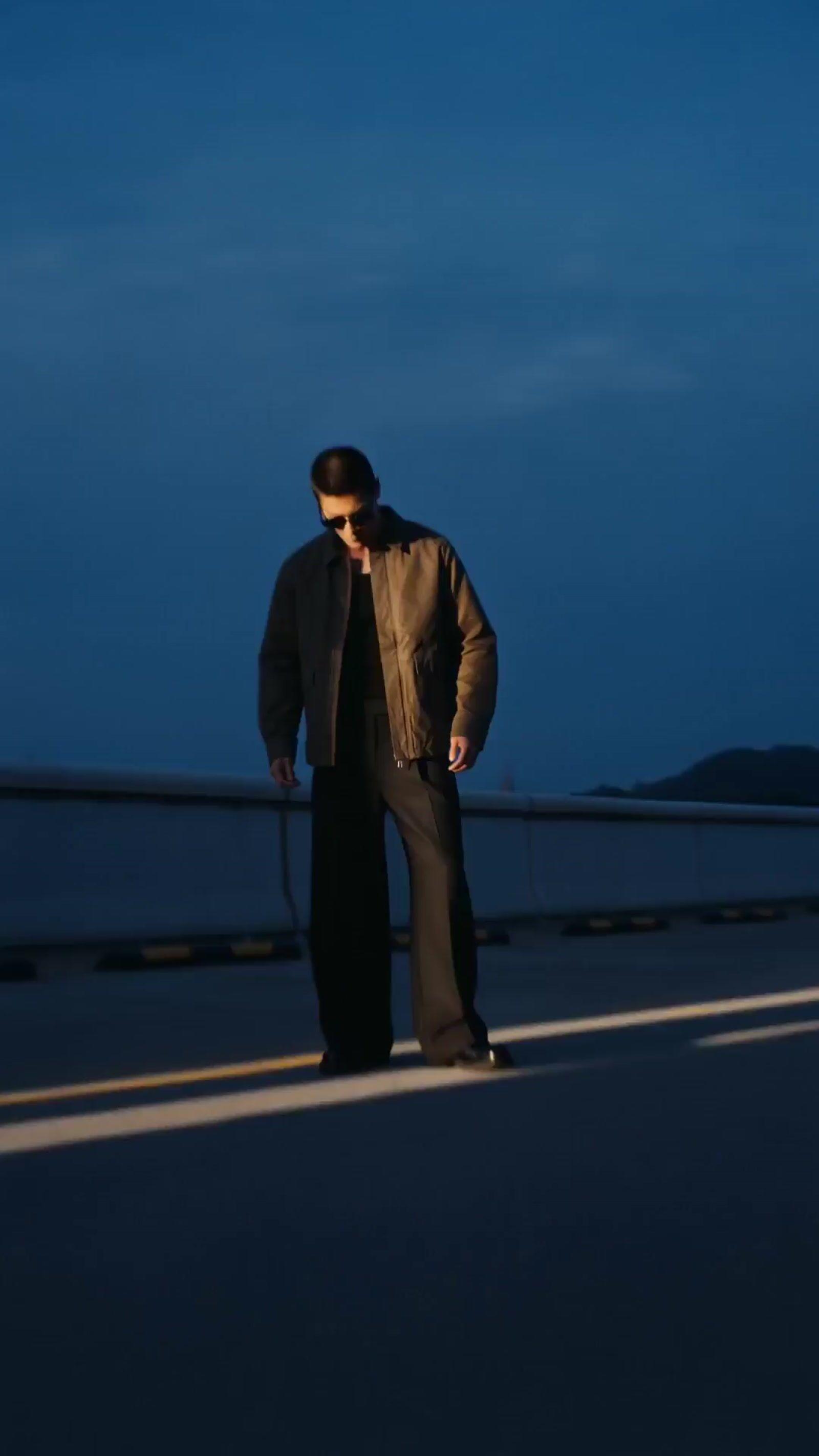 a man standing on the side of a road at night