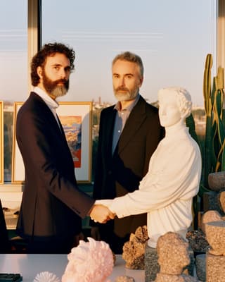 two men shaking hands in front of a statue
