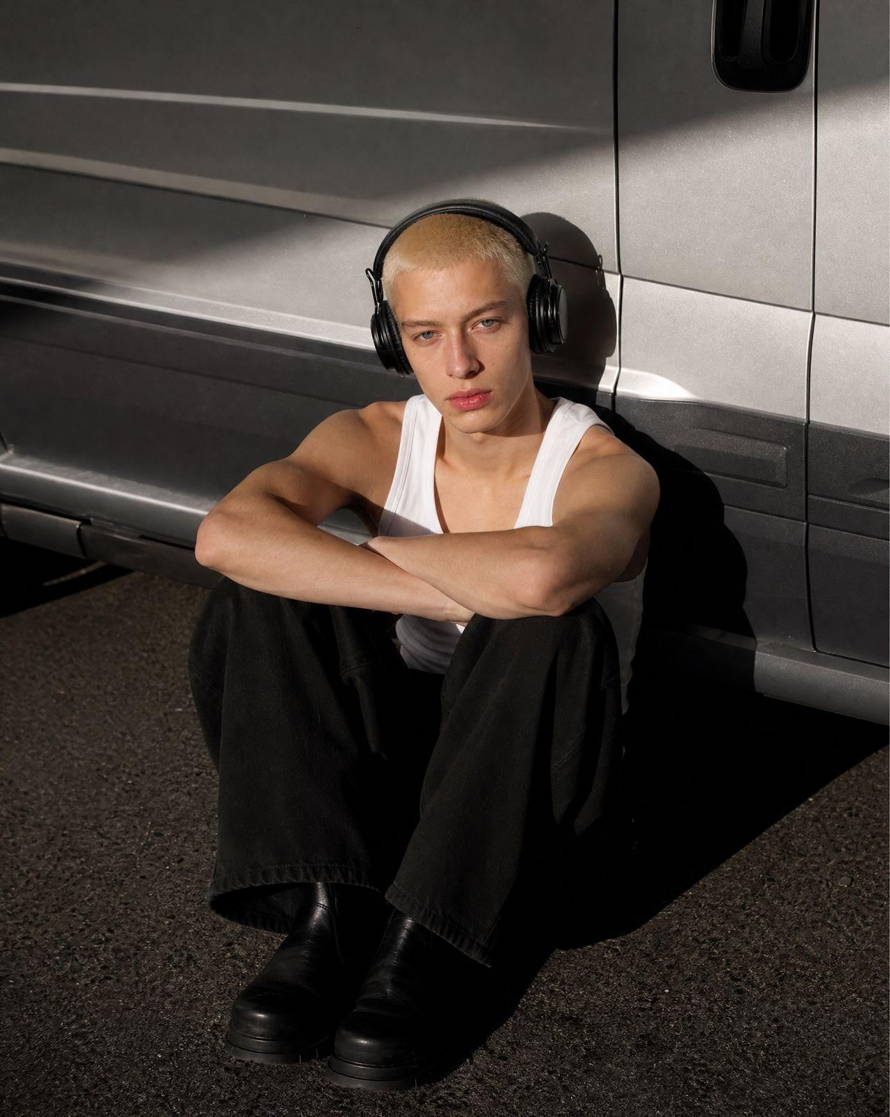 a man with headphones sitting in front of a van
