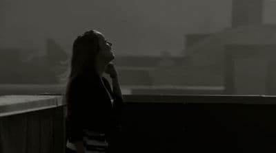 a woman standing on a balcony talking on a cell phone