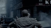 a man in a trench coat walking down a street