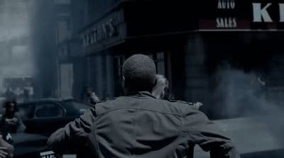 a man in a trench coat walking down a street