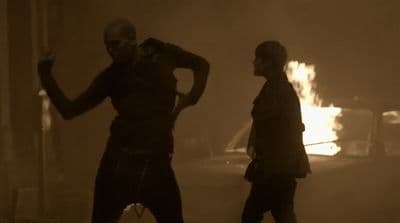 a couple of people standing in front of a fire