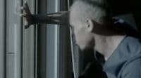 a man in a blue shirt looking out of a window