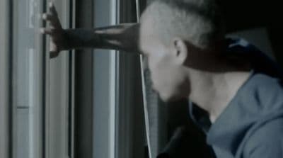 a man in a blue shirt looking out of a window