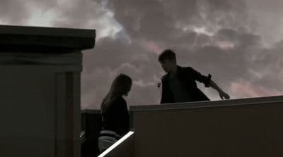 a man and a woman standing on top of a roof
