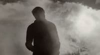 a man standing in front of a cloudy sky