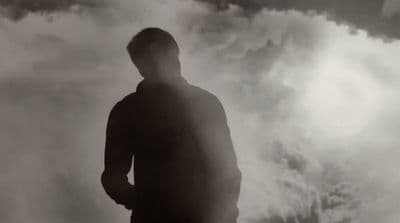 a man standing in front of a cloudy sky