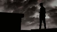 a man standing on top of a roof under a cloudy sky