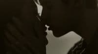 a black and white photo of a man kissing a woman
