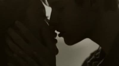 a black and white photo of a man kissing a woman