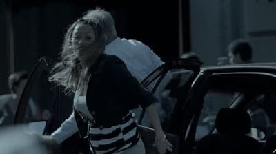 a woman walking out of a car with a man in the background