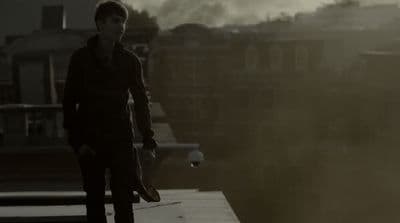 a man standing on top of a roof next to a tall building