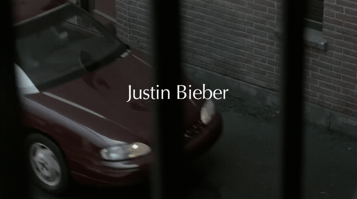 a red car behind bars in front of a brick wall