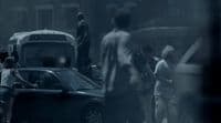 a group of people standing around a car in the rain